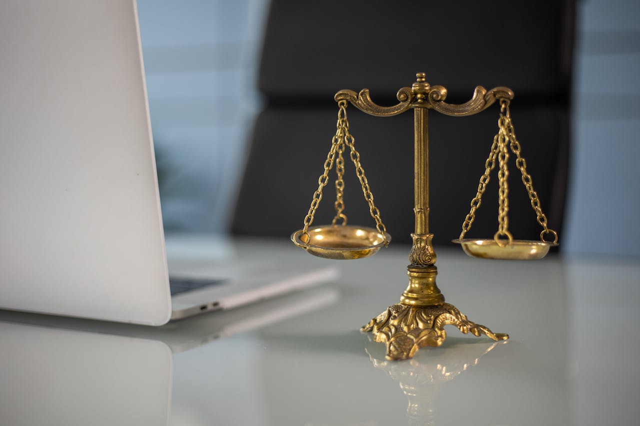 Services Golden justice scales on a desk beside a laptop, symbolizing law and balance.