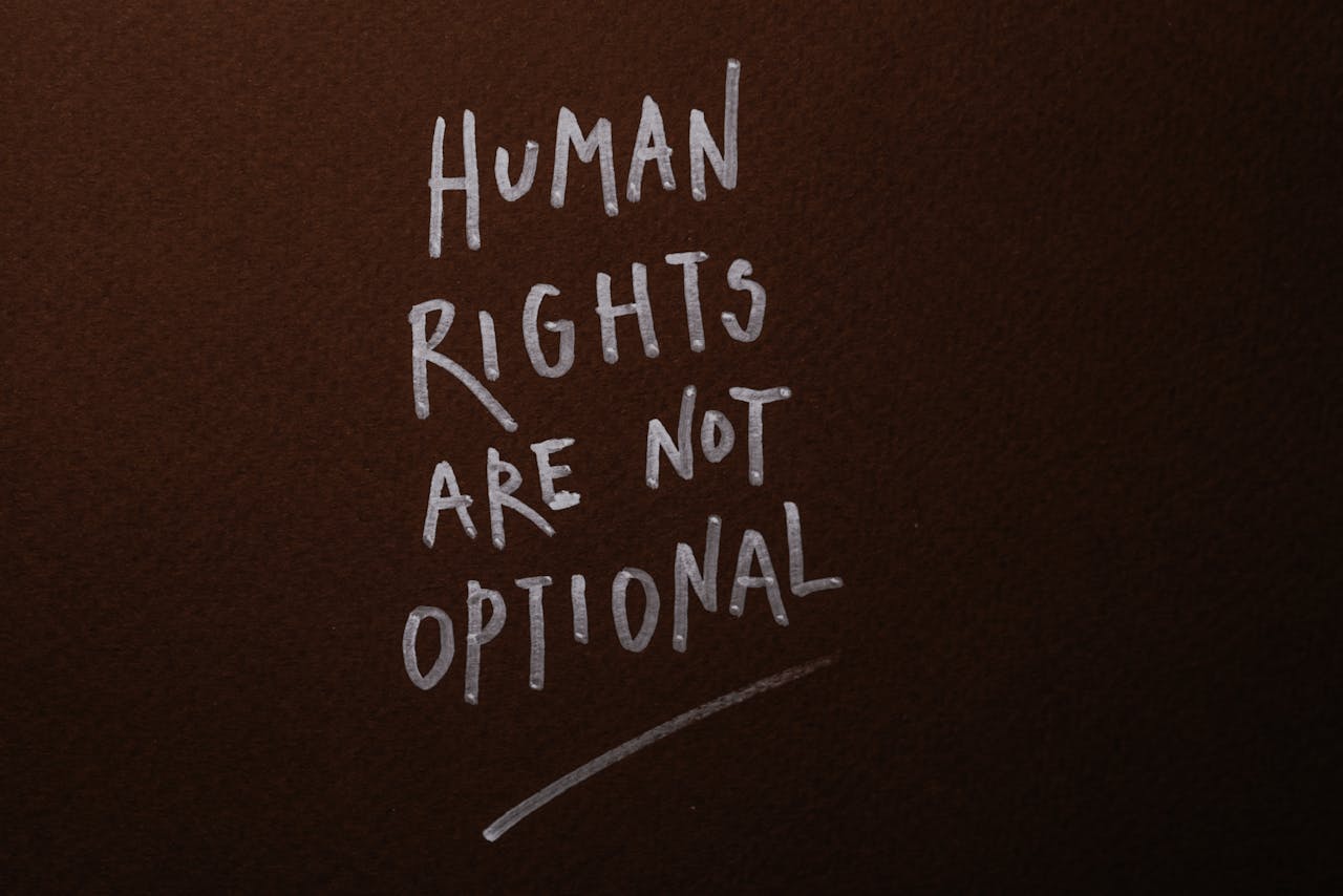 Handwritten message advocating for human rights on a rich brown background.