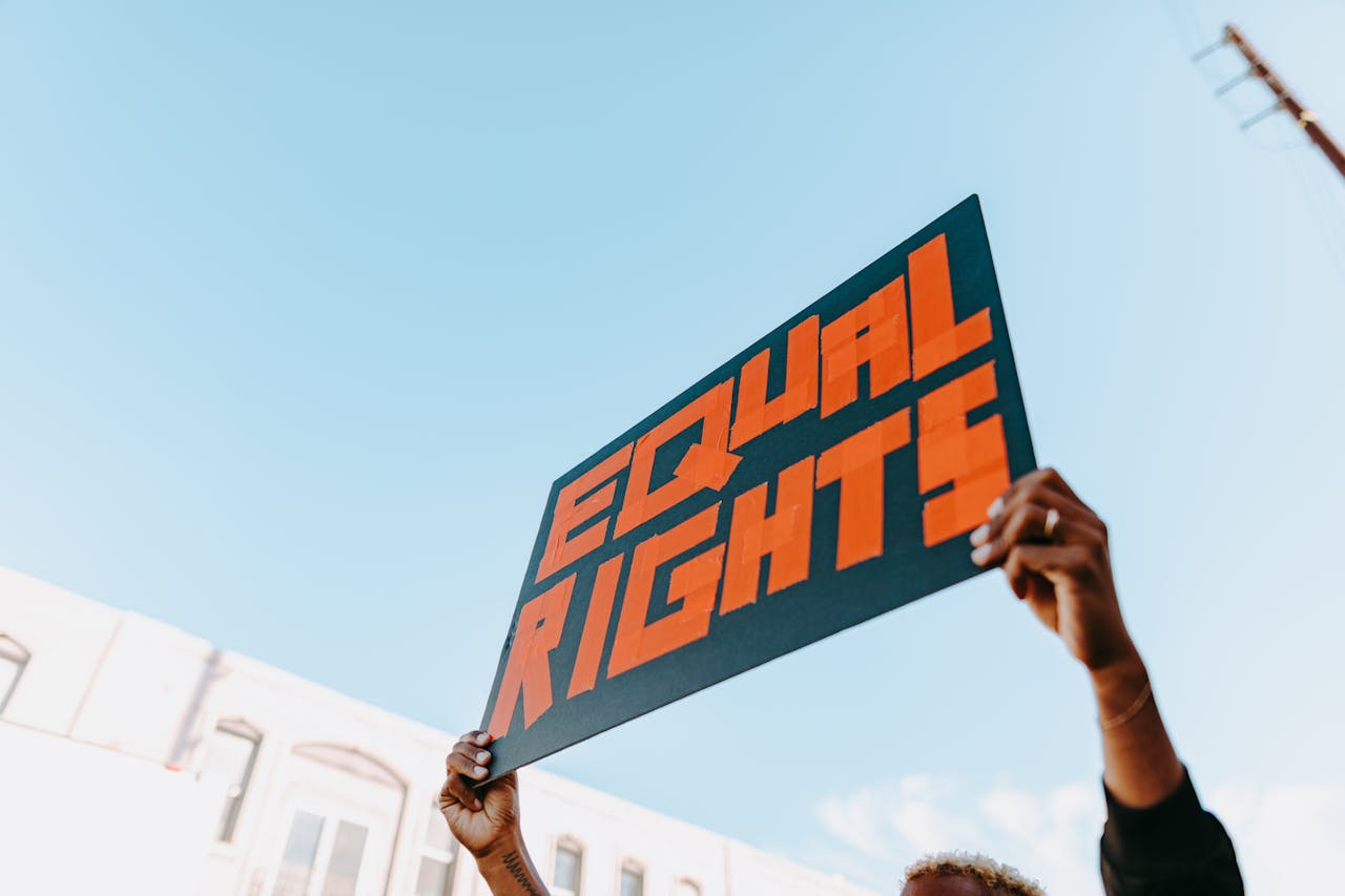 Services Hands holding a bold equal rights sign at an outdoor protest.
